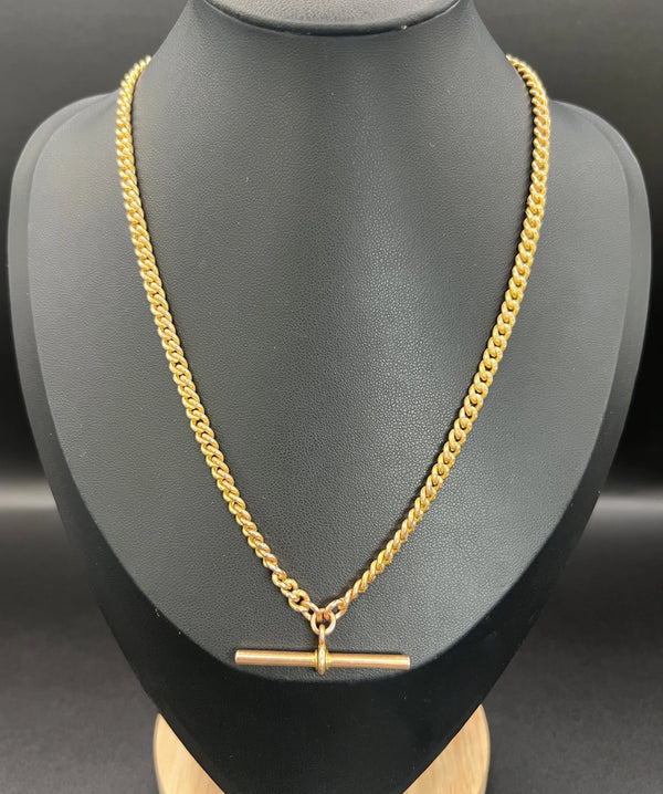 A yellow gold curb link Albert watch chain, on a black jewellery bust