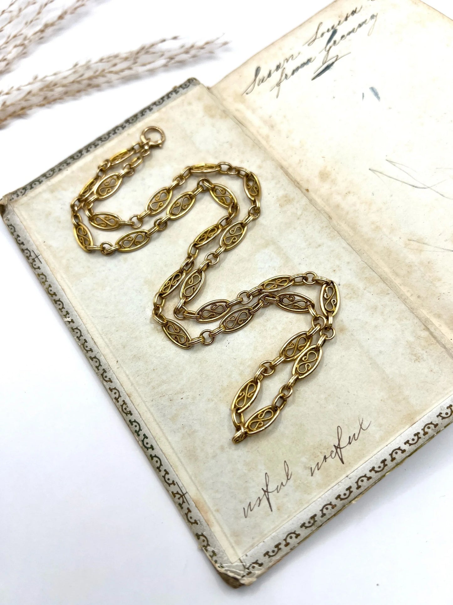 A yellow gold fancy link chain lying on an antique book