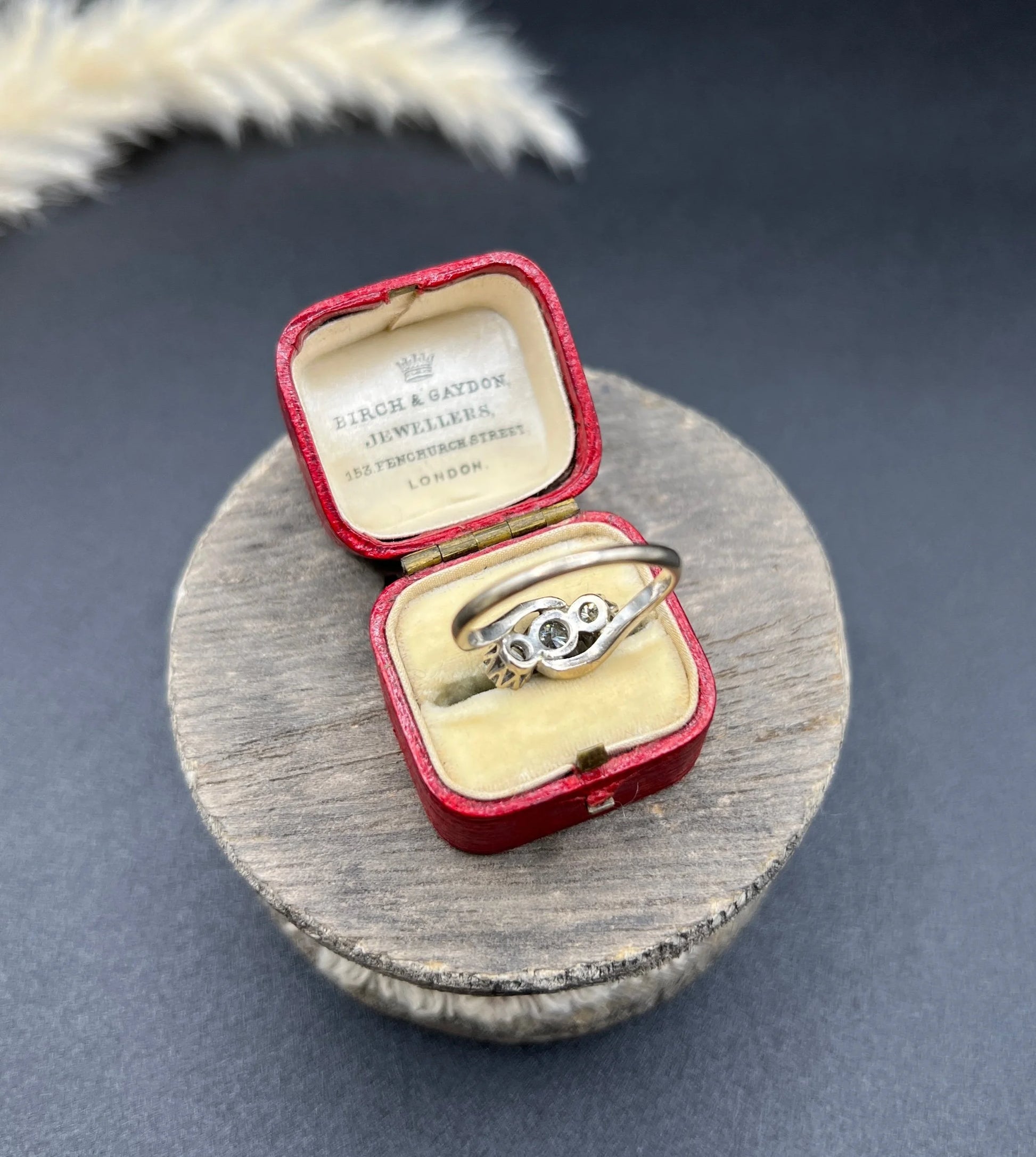 A three stone diamond crossover ring, in a red antique ring box