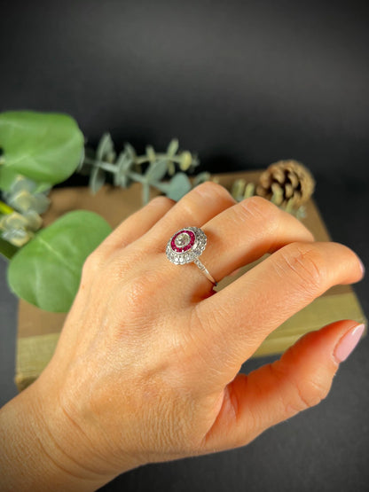 A round cluster ring with rubies and diamonds in white gold, modelled on a hand