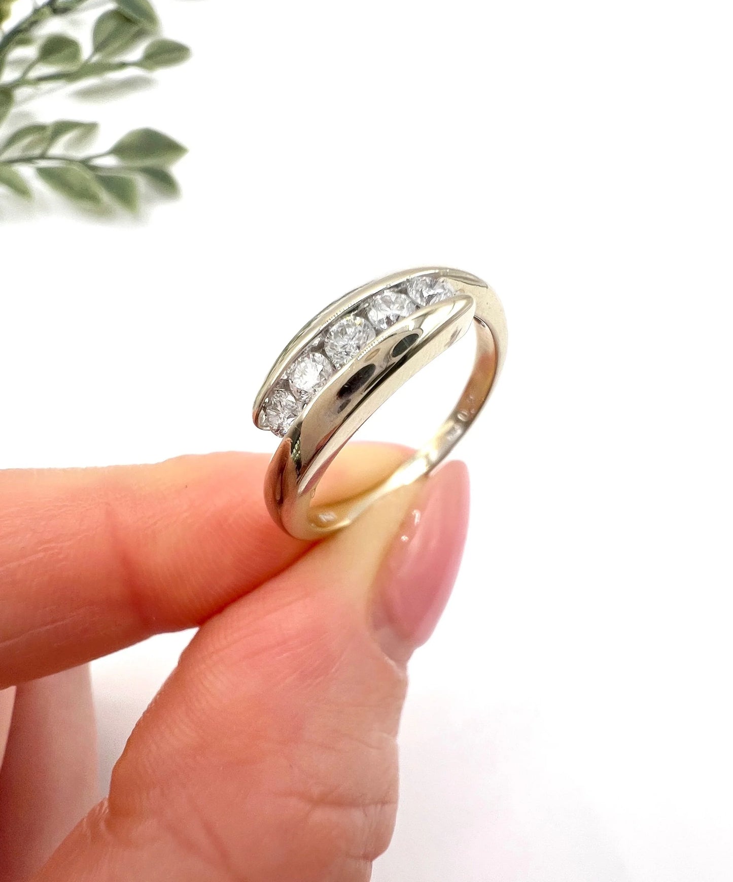 A five stone brilliant cut diamond ring in white gold, held in a hand