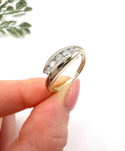A five stone brilliant cut diamond ring in white gold, held in a hand