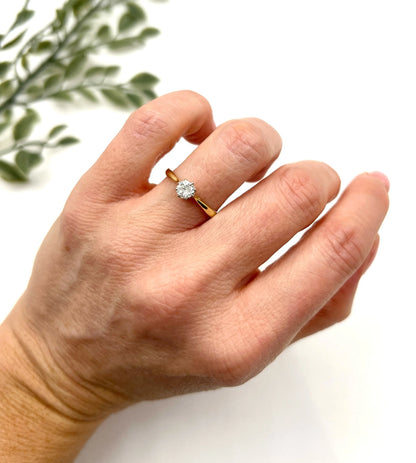 A single stone brilliant cut diamond ring claw set in platinum and yellow gold, modelled on a hand