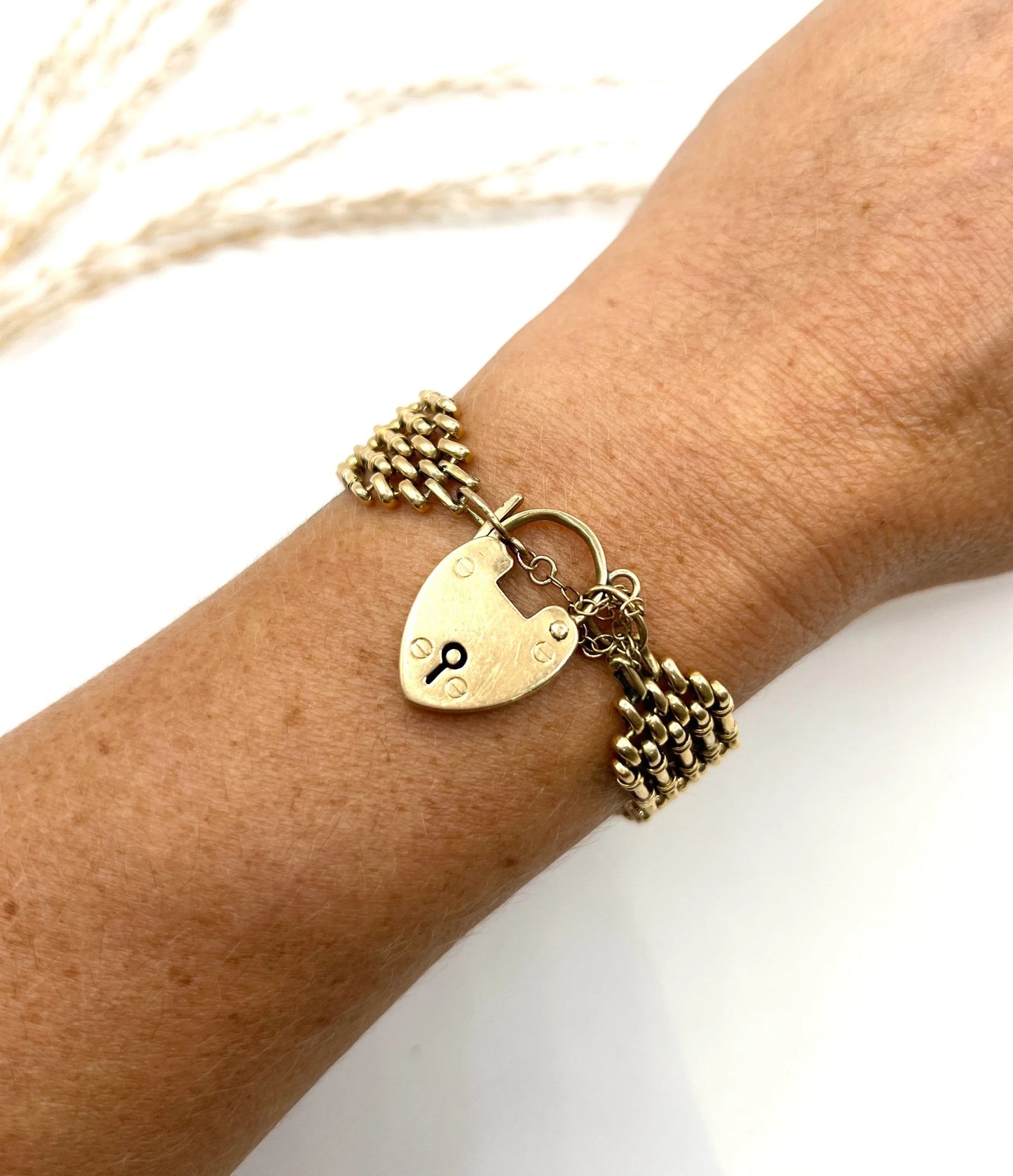 A yellow gold gate bracelet with heart shaped padlock clasp, modelled on a wrist