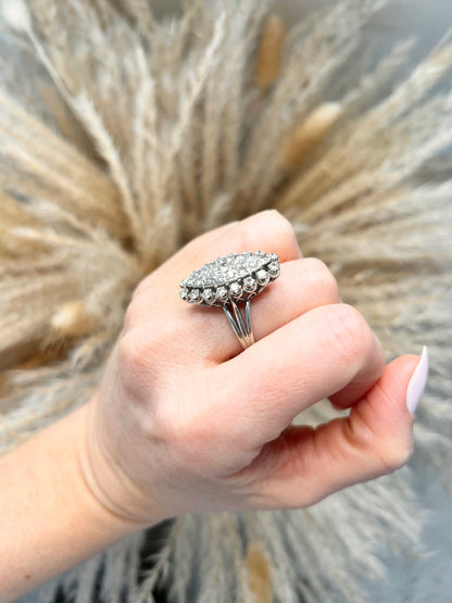A navette shaped diamond cluster ring in white metal, modelled on a hand