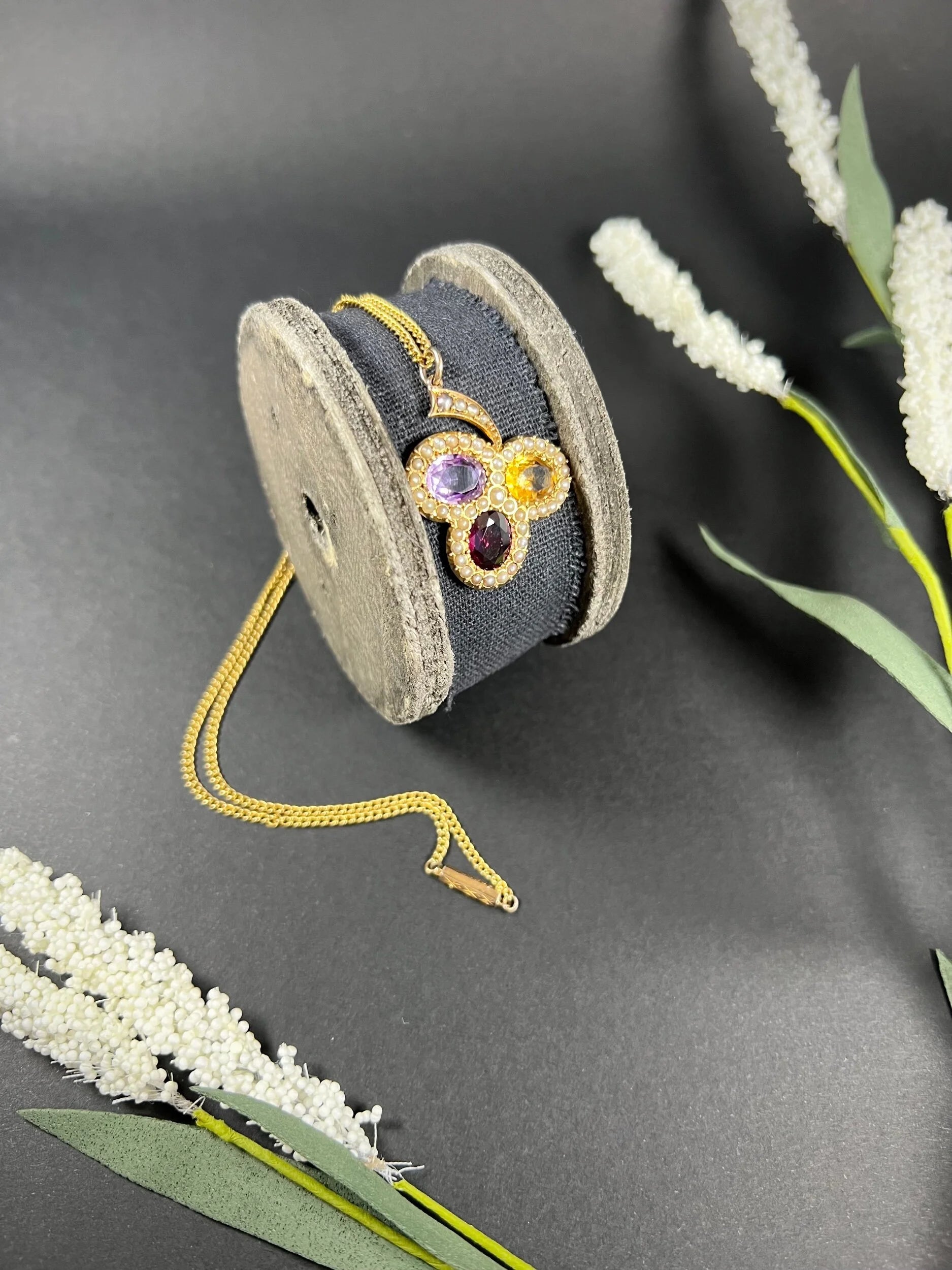 A yellow gold clover pendant with amethyst, citrine, garnet and seed pearls, with a chain