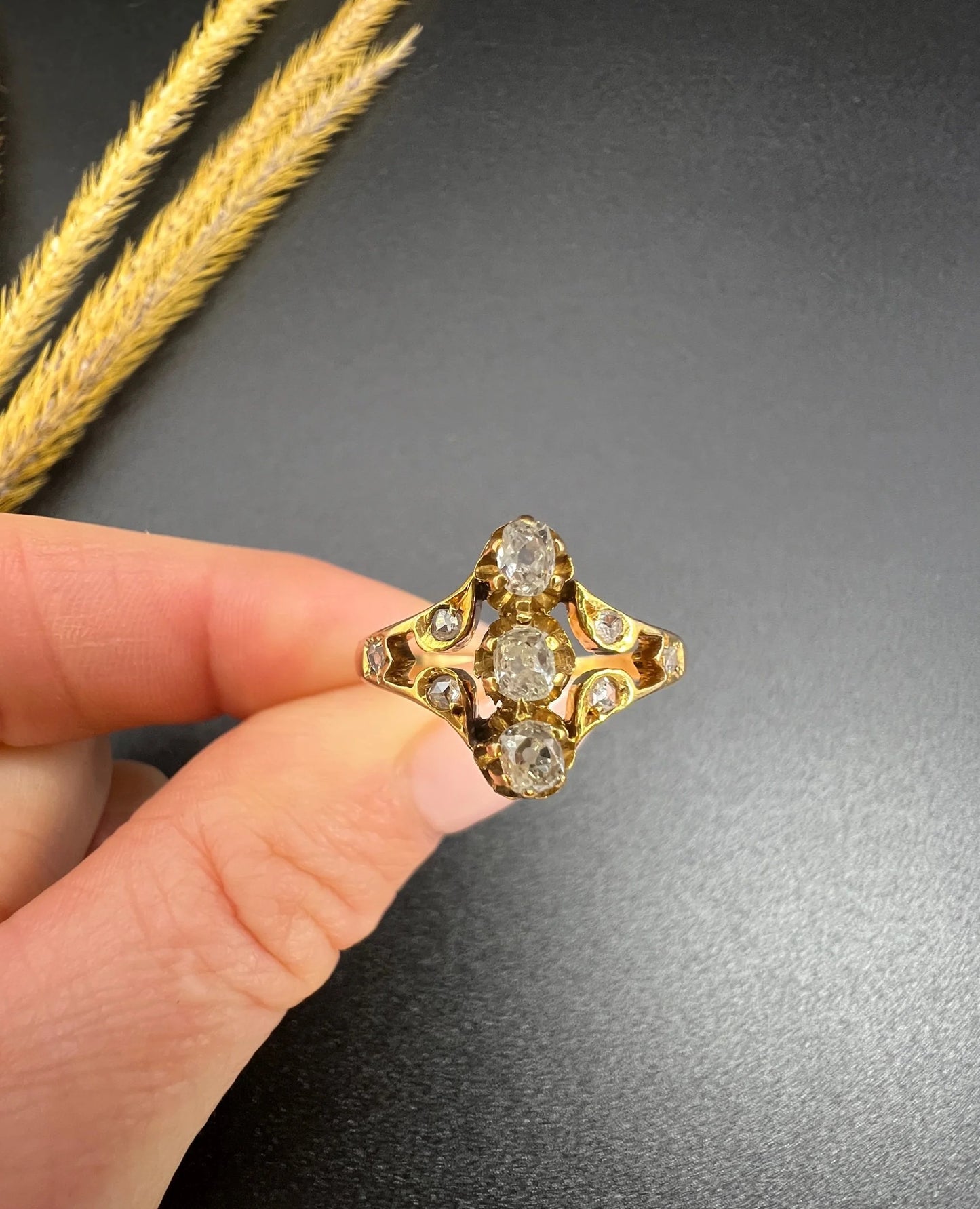 An antique old cut diamond ring in yellow gold, held in a hand