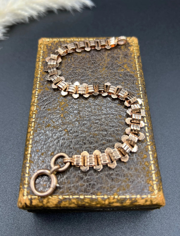 A rose gold fancy link bracelet with a bolt ring clasp