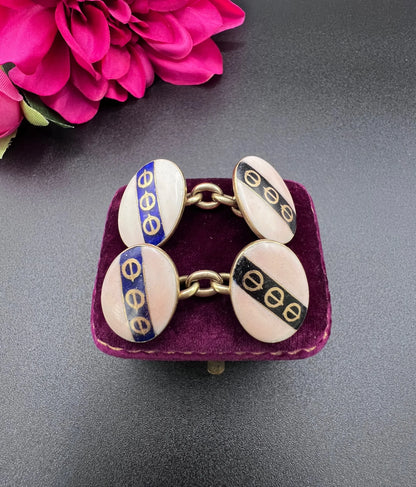 A pair of yellow gold enamel striped cufflinks with chain link fittings, on an antique box