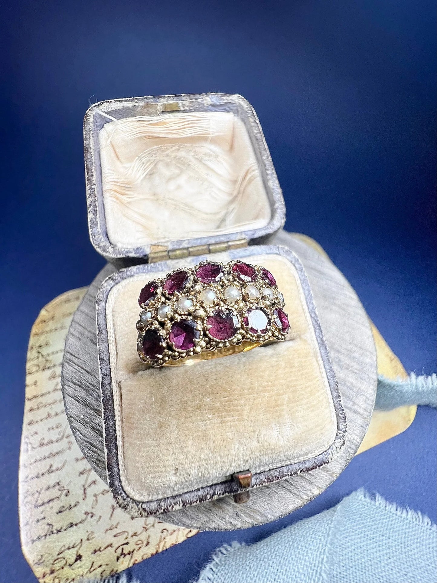 A yellow gold triple row ring with garnets and seed pearls, in a ring box