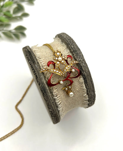 A floral pendant in yellow gold with seed pearls and red enamel, with a chain