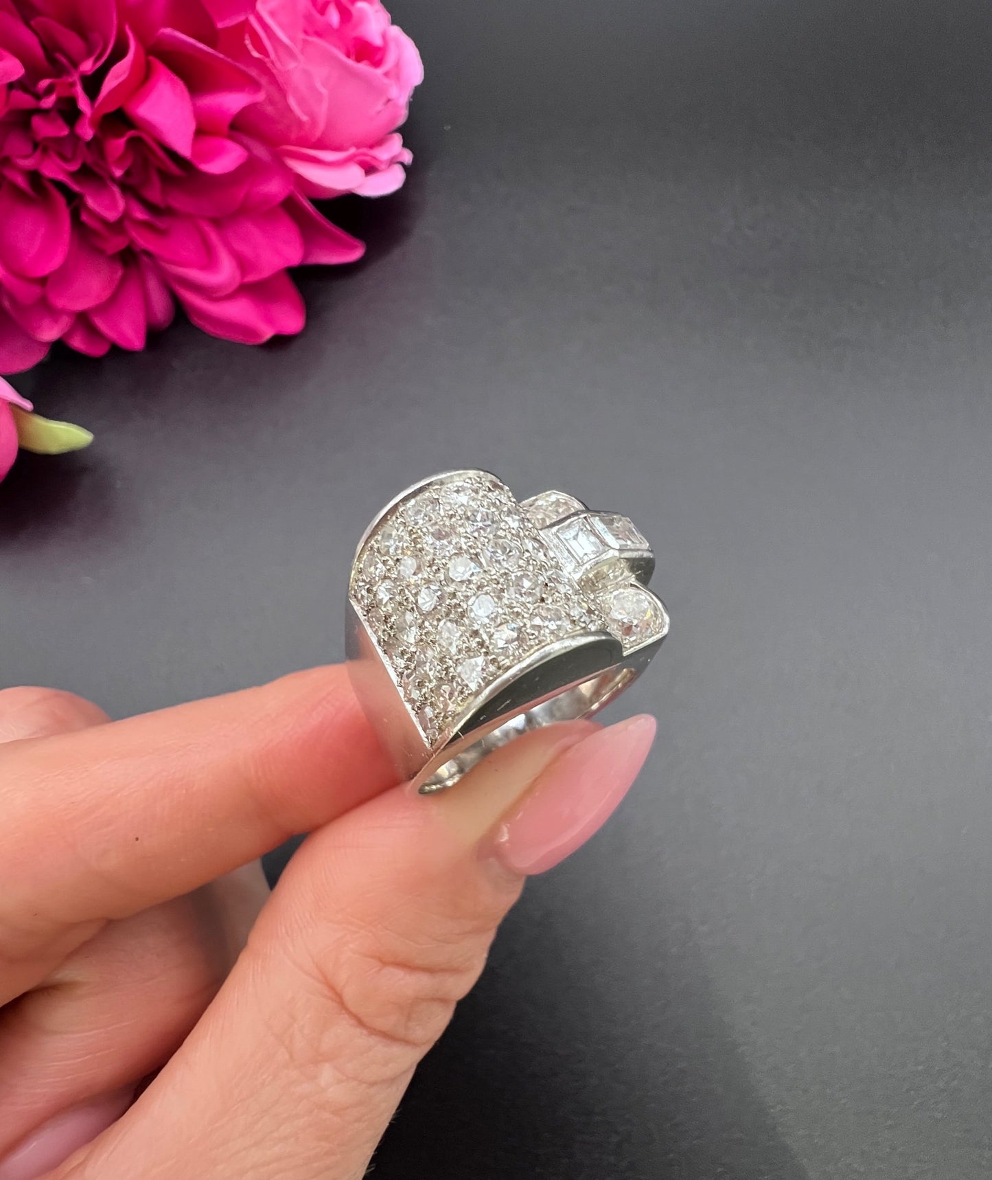A round diamond tank style cocktail ring in platinum, held in a hand