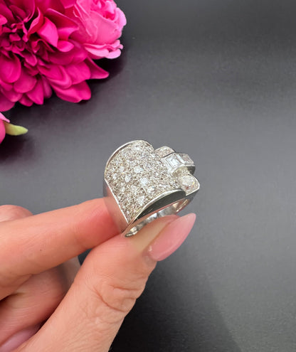 A round diamond tank style cocktail ring in platinum, held in a hand