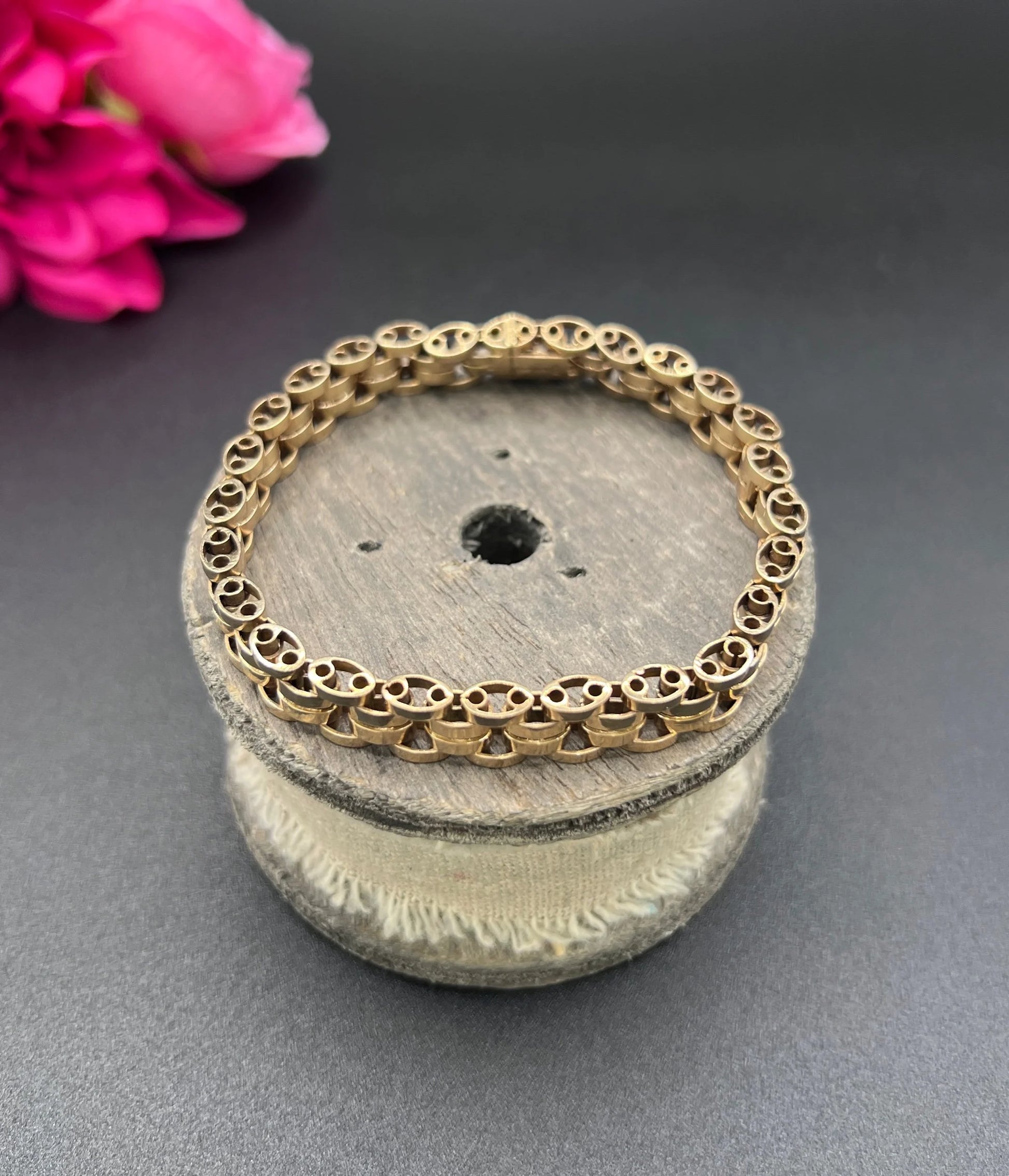 A yellow gold link bracelet, on a wooden spool