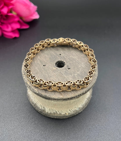 A yellow gold link bracelet, on a wooden spool
