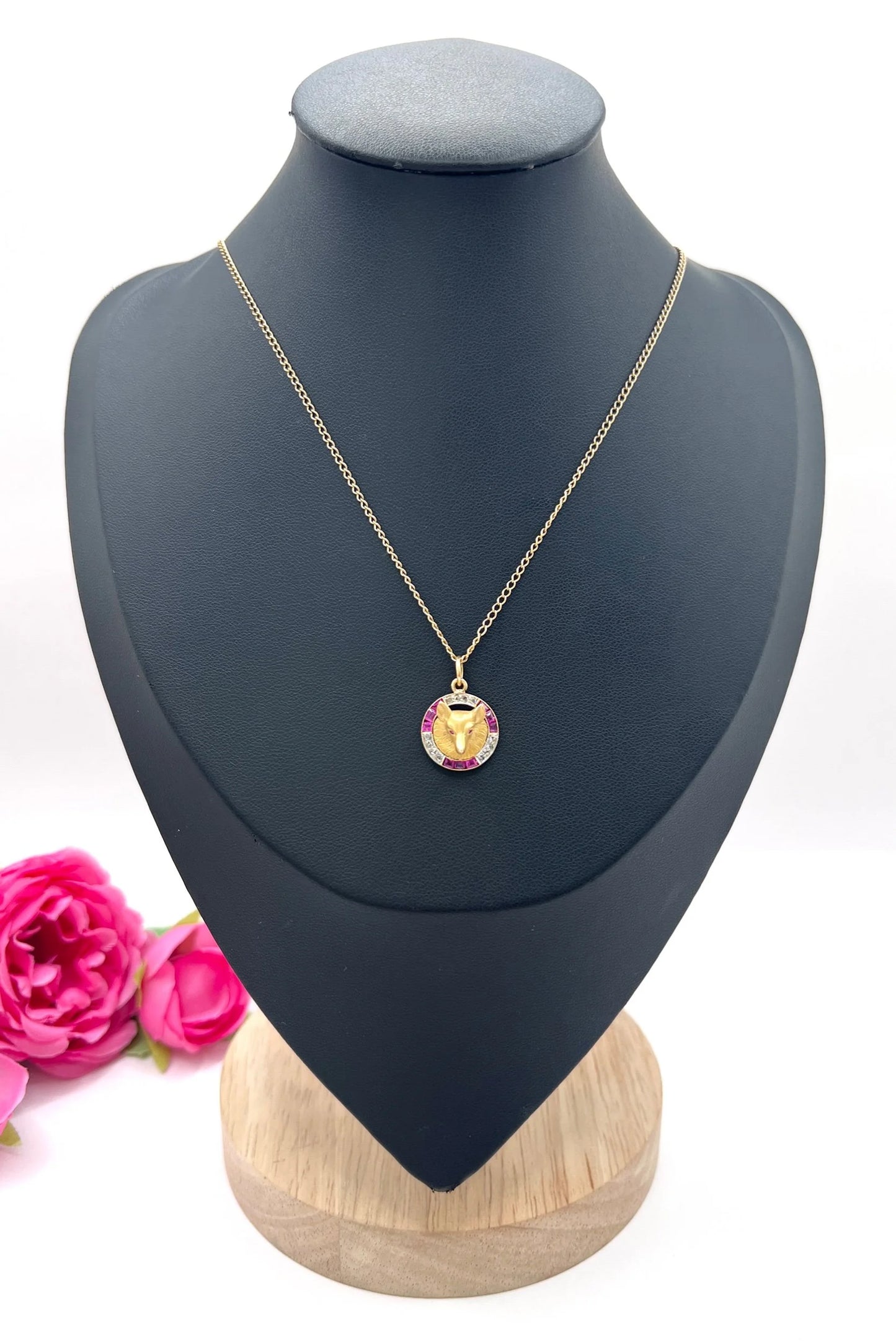 A fox head pendant in yellow gold with a ruby and diamond border, with a gold chain