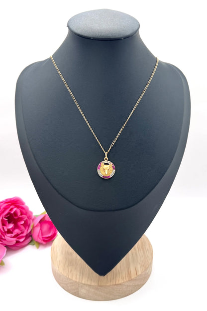 A fox head pendant in yellow gold with a ruby and diamond border, with a gold chain