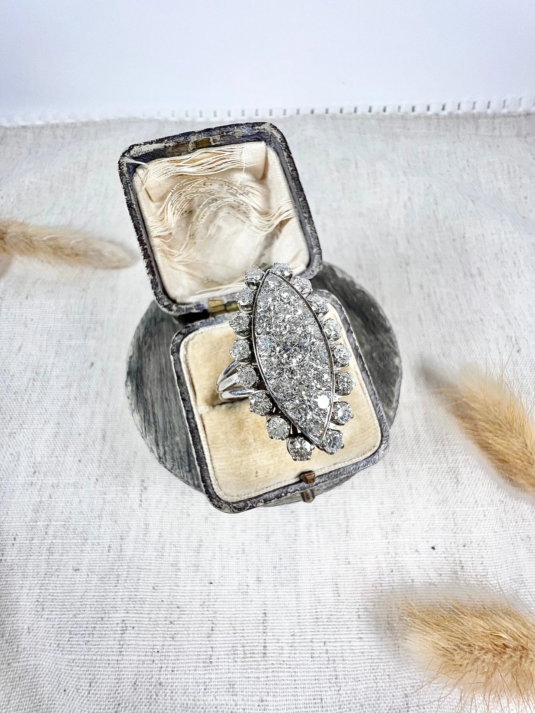 A navette shaped diamond cluster ring in white metal, in an antique ring box