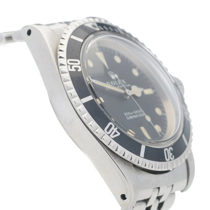 A Rolex Submariner wristwatch in stainless steel with a black dial and jubilee bracelet, on a white background