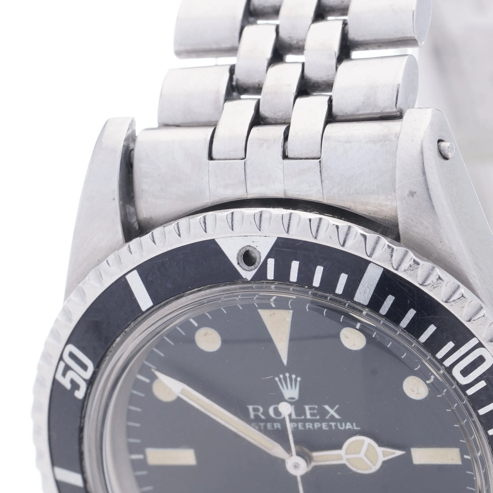 A Rolex Submariner wristwatch in stainless steel with a black dial and jubilee bracelet, on a white background