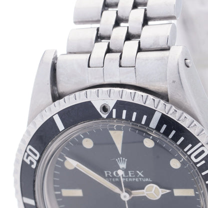 A Rolex Submariner wristwatch in stainless steel with a black dial and jubilee bracelet, on a white background
