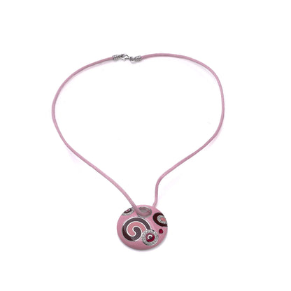 A pink enamel circular pendant with diamonds on a pink cord, on a white background