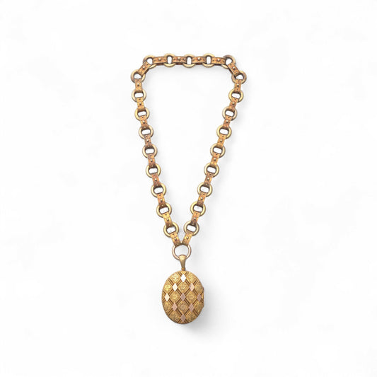 An antique yellow and rose gold fancy link necklace with an oval locket pendant, on a white background