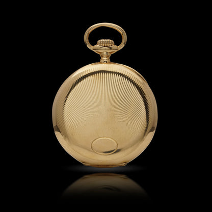 The back of a yellow gold pocket watch, on a black background