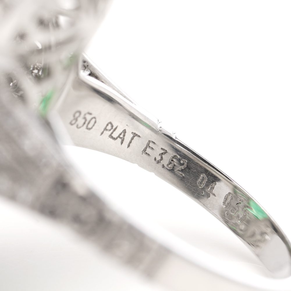 Oval cut emerald ring surround by emeralds and diamonds set in platinum.