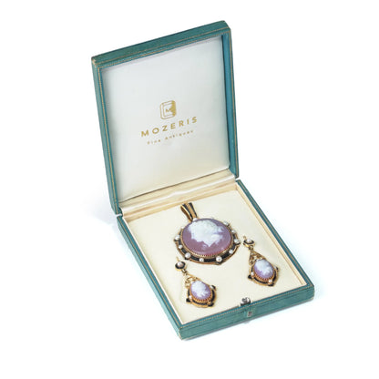 A cameo pendant and earrings suite in yellow gold with pearls and black enamel details, in a fitted case