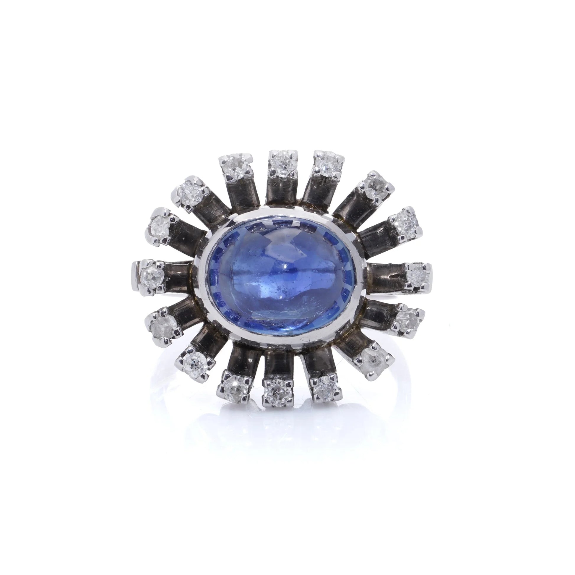 A cabochon blue sapphire and diamond ring in platinum, on a white background