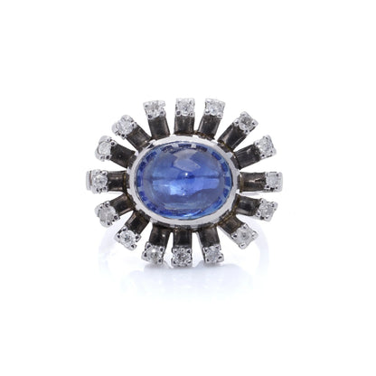 A cabochon blue sapphire and diamond ring in platinum, on a white background