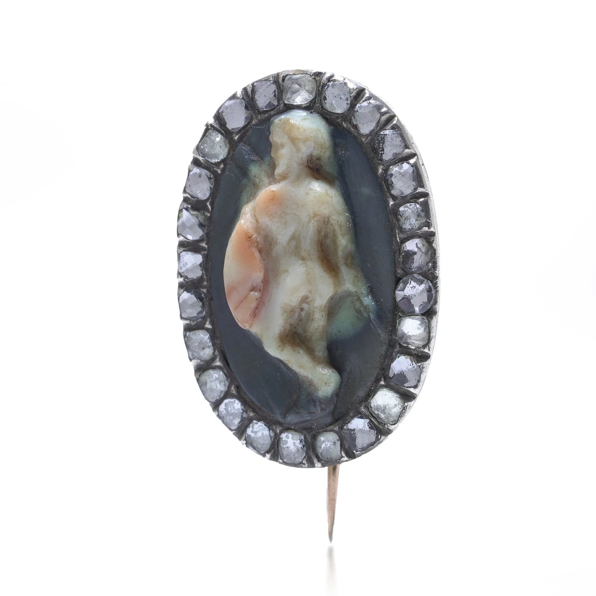 An oval cameo brooch depicting a nude figure, with diamonds around the border, on a white background
