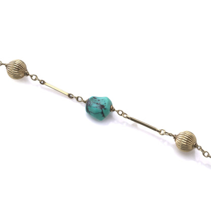 A yellow gold long chain necklace with turquoise nuggets, on a white background