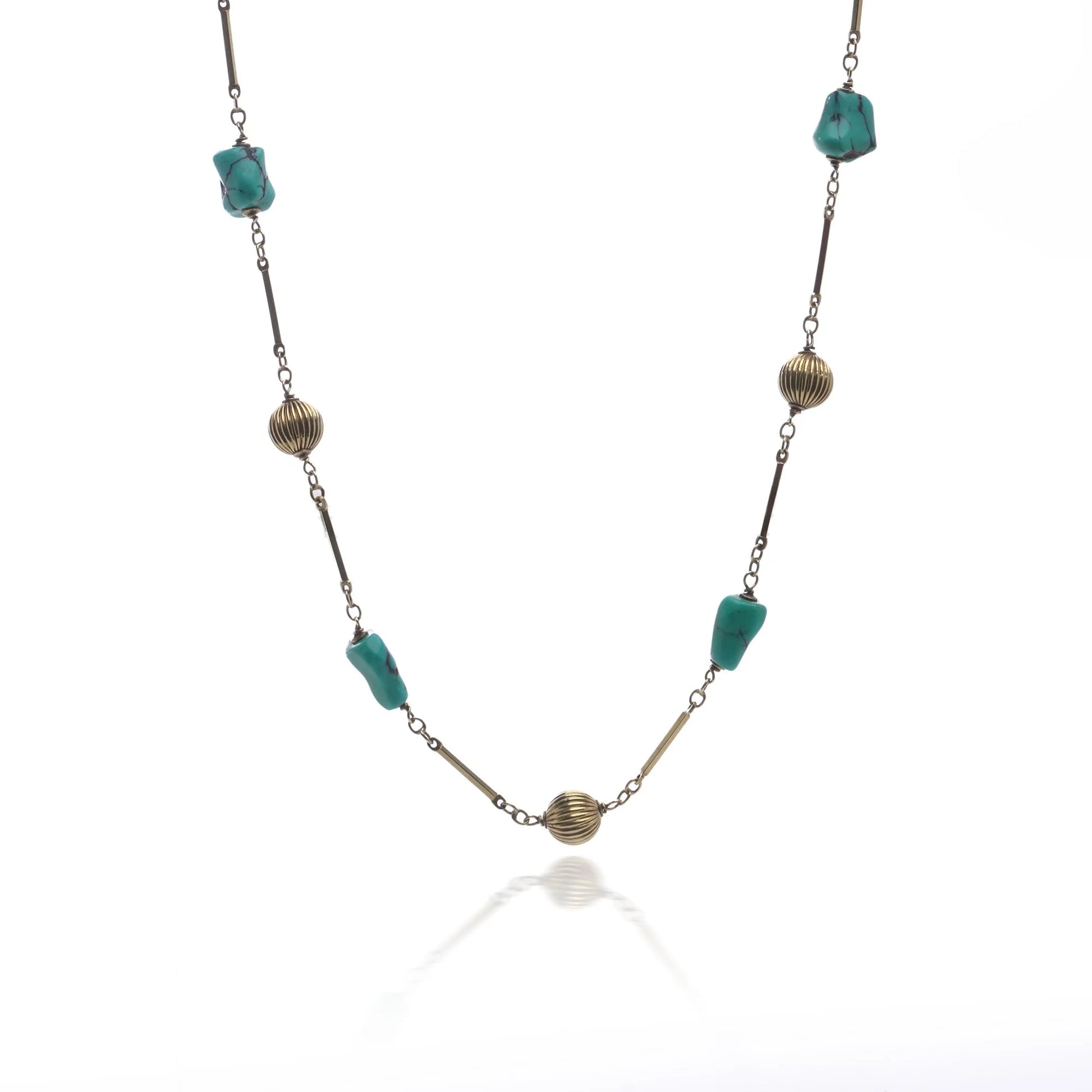 A yellow gold long chain necklace with turquoise nuggets, on a white background