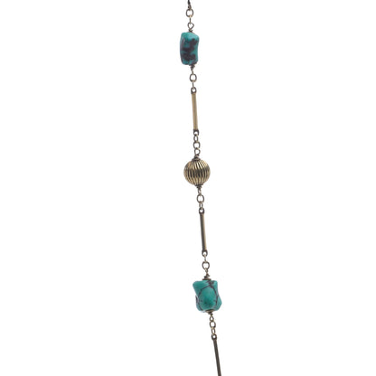 A yellow gold long chain necklace with turquoise nuggets, on a white background