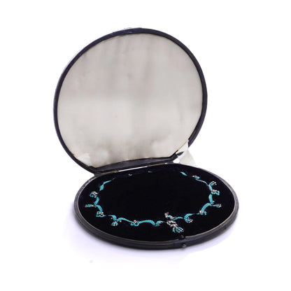 An antique turquoise bead and pearl fancy necklace with a bird motif, in an antique fitted case, on a white background