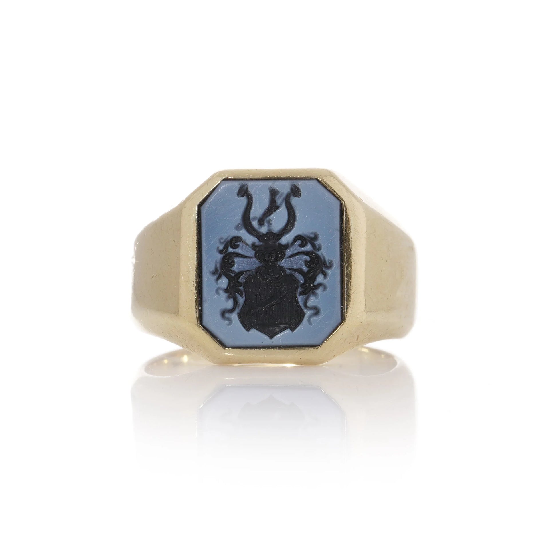 A yellow gold ring with an octagonal sardonyx intaglio, on a white background