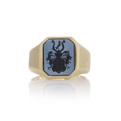 A yellow gold ring with an octagonal sardonyx intaglio, on a white background