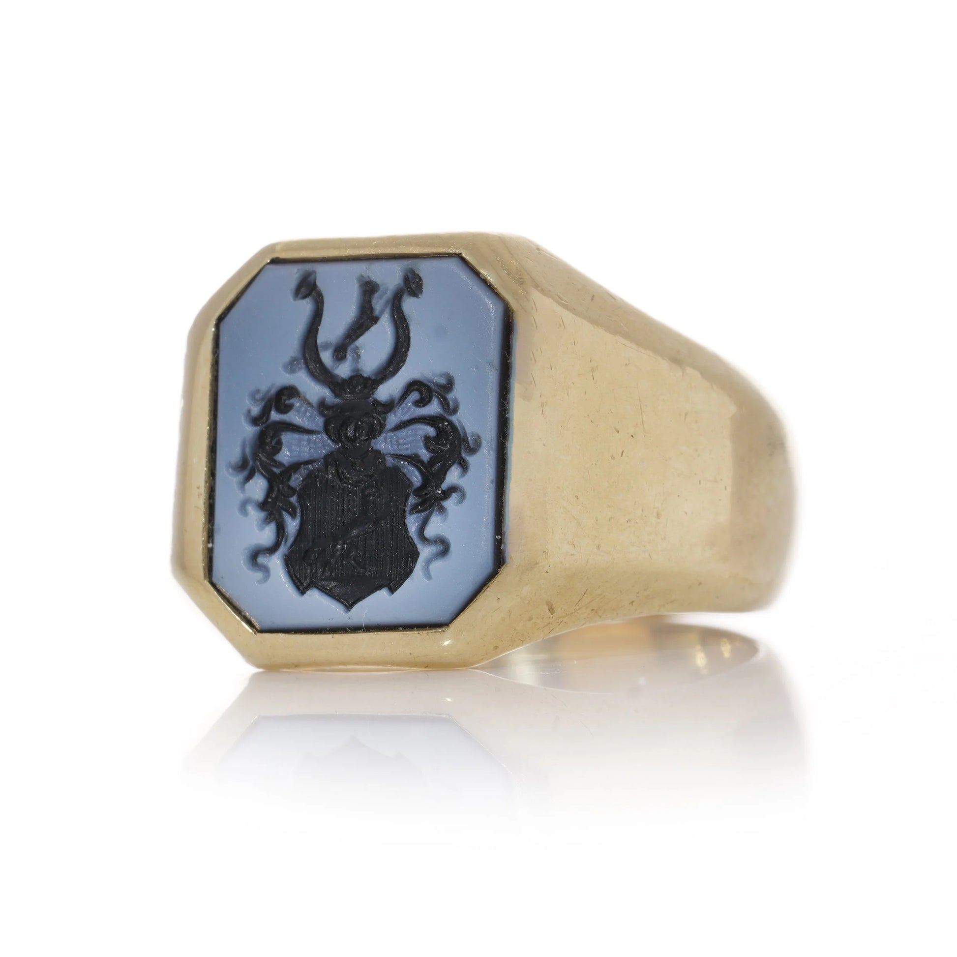 A yellow gold ring with an octagonal sardonyx intaglio, on a white background