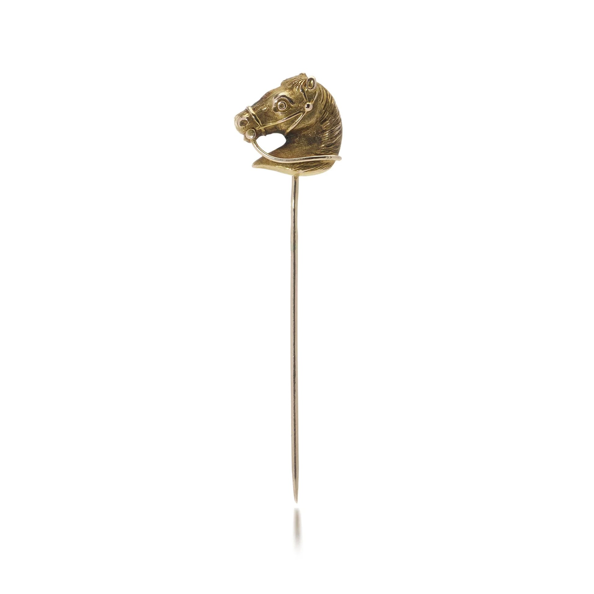 A yellow gold tie or stick pin featuring a horse's head, on a white background