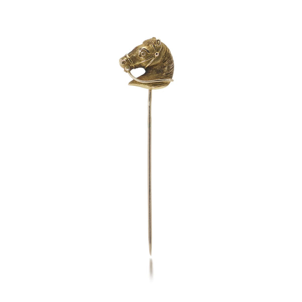 A yellow gold tie or stick pin featuring a horse's head, on a white background