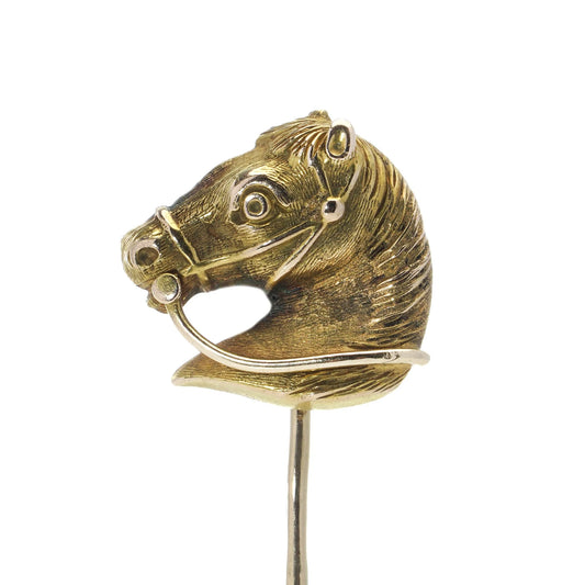 A yellow gold tie or stick pin featuring a horse's head, on a white background