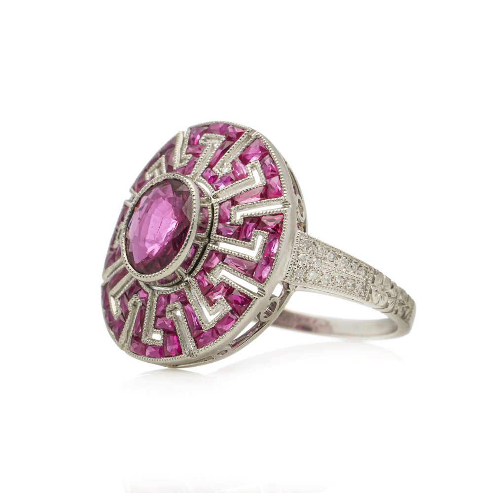 Platinum oval ruby cluster ring surrounded by rubies diamonds.