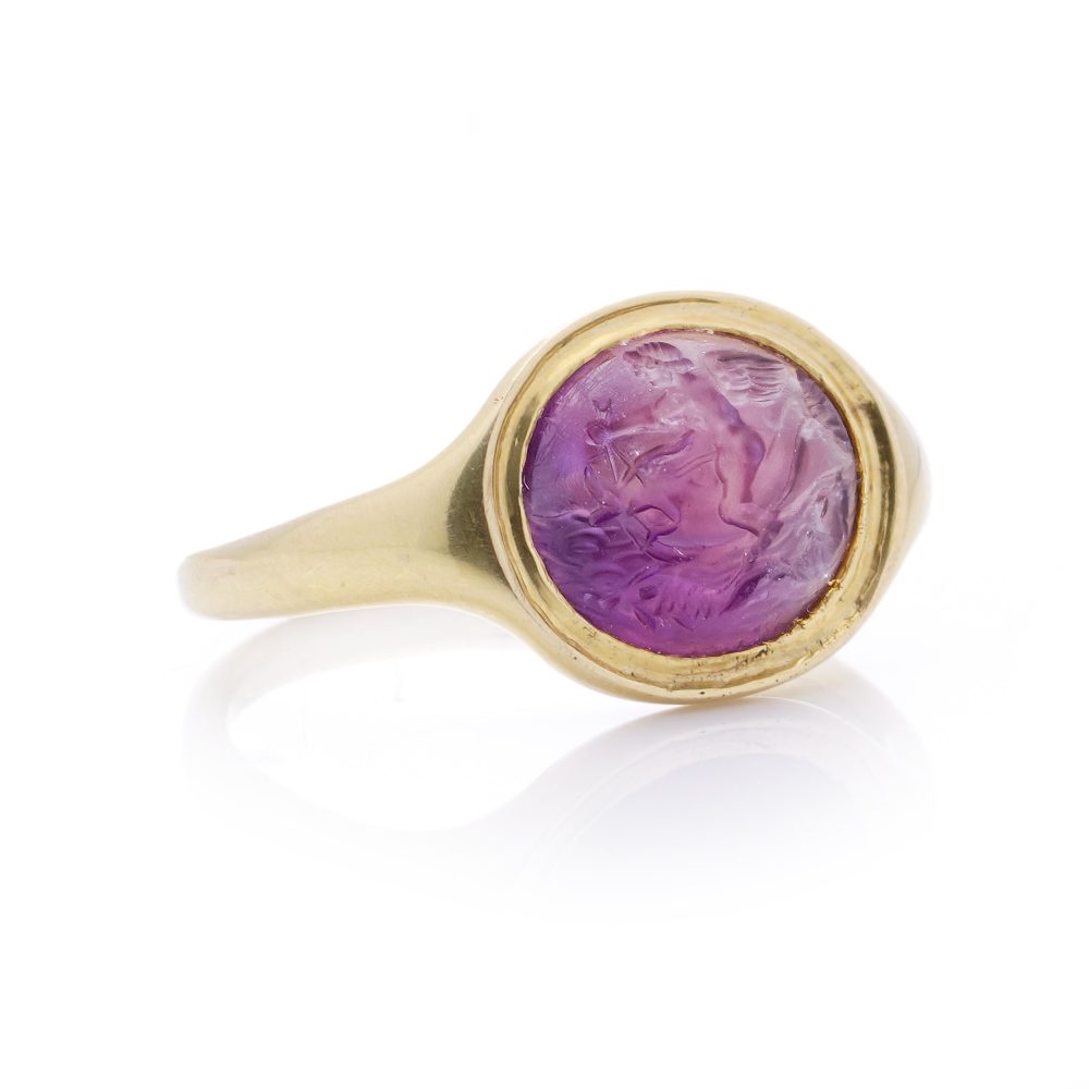 Roman carved intaglio amethyst ring featuring Eros riding a dolphin mounted in gold.