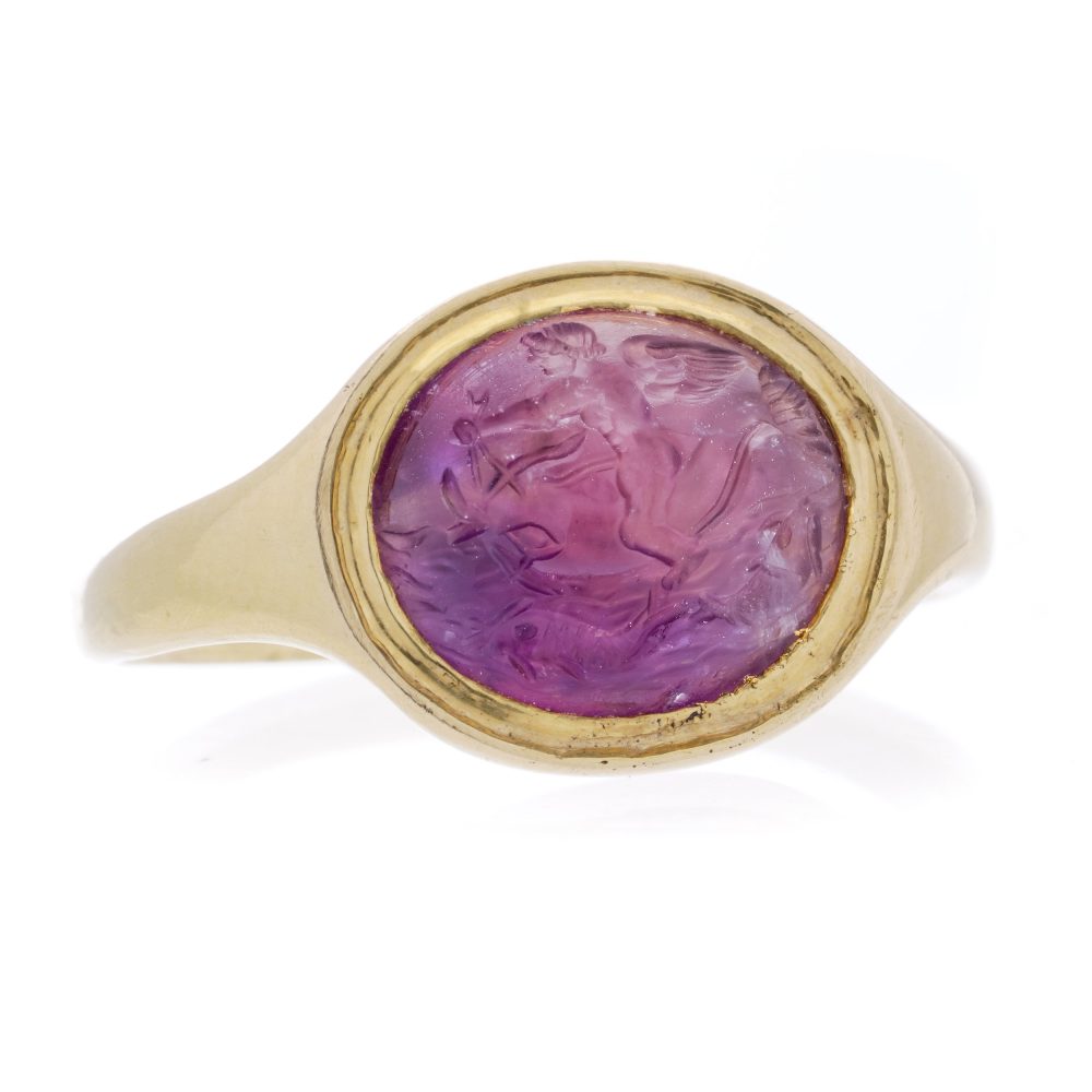 Roman carved intaglio amethyst ring featuring Eros riding a dolphin mounted in gold.