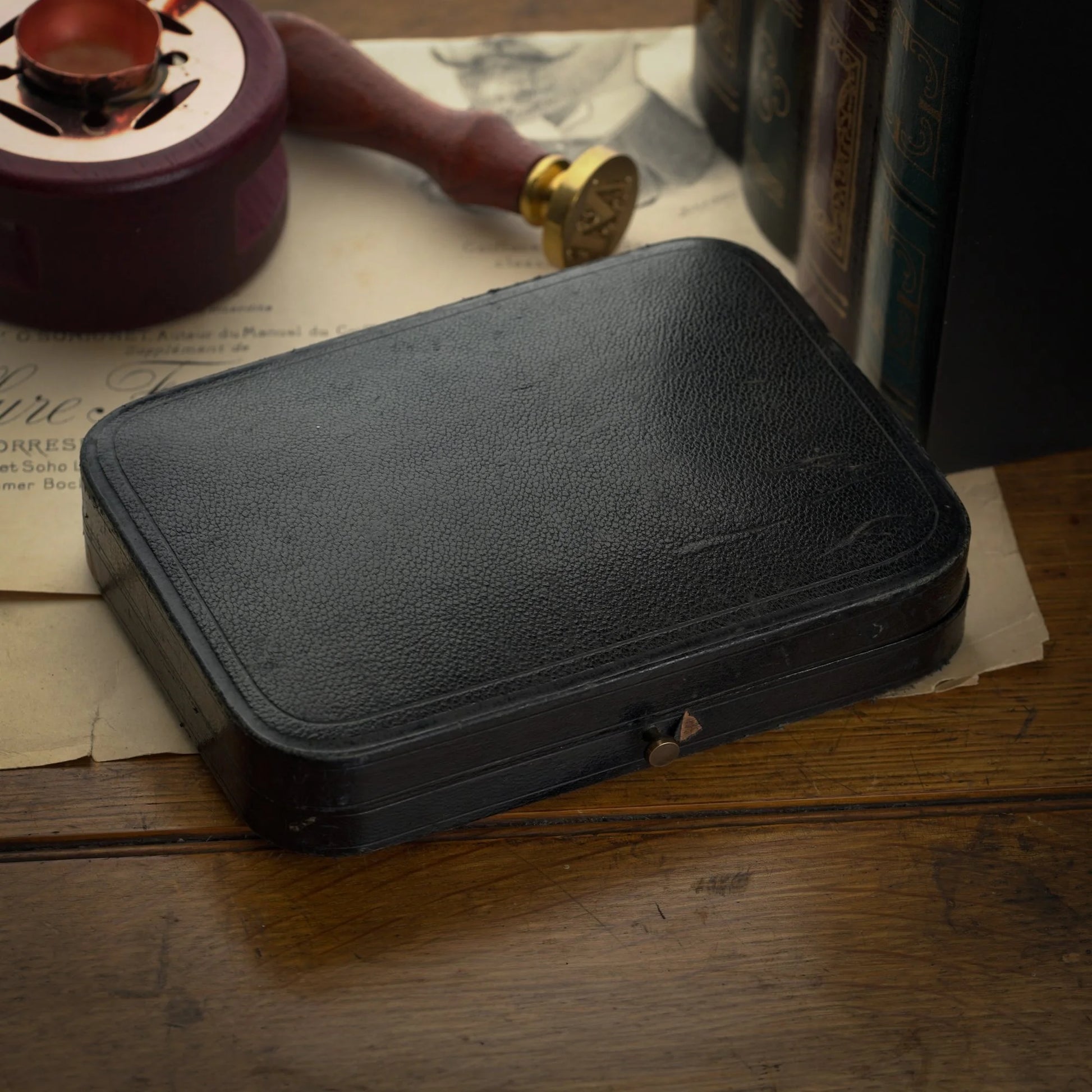 Black leather case on a wooden surface with vintage items