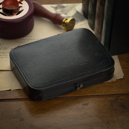 Black leather case on a wooden surface with vintage items