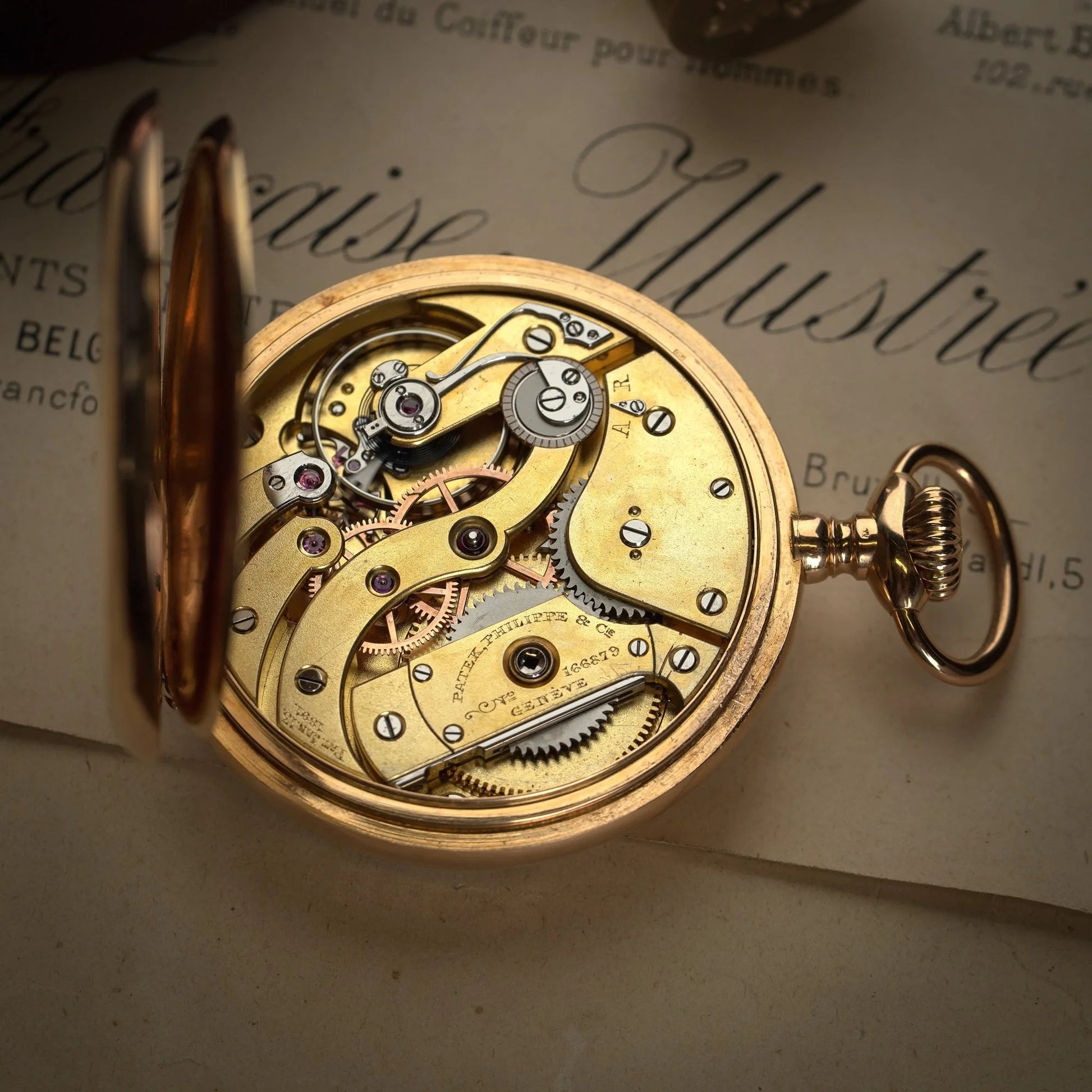 A yellow gold pocket watch with an open back showing the movement, engraved Patek Phillipe Geneve