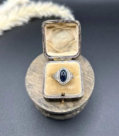 An oval cabochon sapphire and diamond fancy cluster ring in yellow and white gold, in a ring box